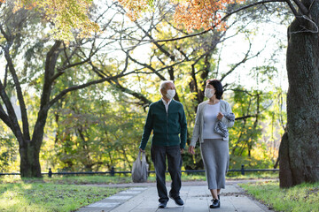 Obraz premium マスクをつけて公園を散歩する日本人シニア夫婦