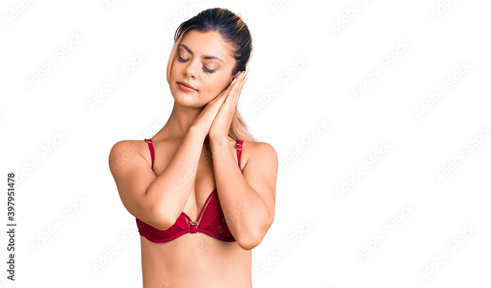 Poster Young beautiful woman wearing bikini sleeping tired dreaming and posing with hands together while smiling with closed eyes.