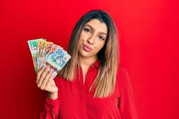 Beautiful brunette woman holding australian dollars looking sleepy and tired, exhausted for fatigue and hangover, lazy eyes in the morning.