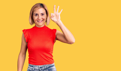 Young blonde woman wearing casual clothes smiling positive doing ok sign with hand and fingers. successful expression.