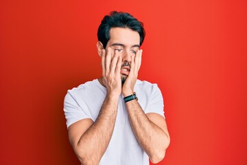 Young hispanic man wearing casual white tshirt tired hands covering face, depression and sadness, upset and irritated for problem