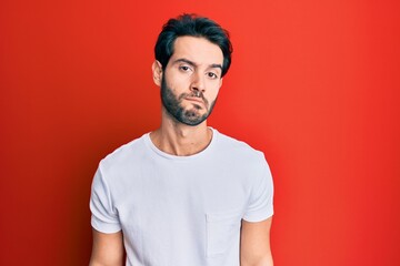 Obraz premium Young hispanic man wearing casual white tshirt looking sleepy and tired, exhausted for fatigue and hangover, lazy eyes in the morning.