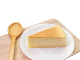 The close up of sliced yummy cheesecake bakery sweet dessert and wooden spoon on wood cutting board isolated on white background.