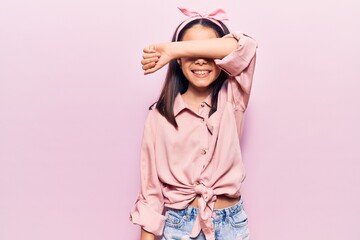 Beautiful child girl wearing casual clothes covering eyes with arm smiling cheerful and funny....