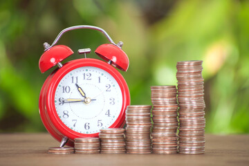 An alarm clock and a row of increasing dollar coins