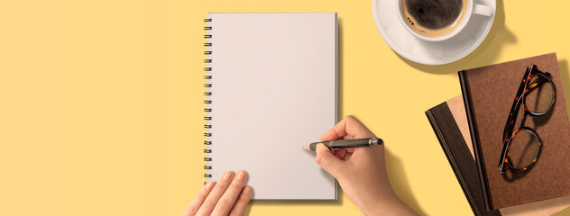 テーブルの上で、文字をノートに書き込んでいる手のイメージビジュアル