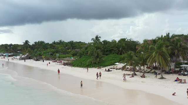 Detalle a&eacute;reo de Playa Para&iacute;so, el drone volando de forma lateral frente a un nutrido grupo de palmeras tropicales con turistas en la playa.