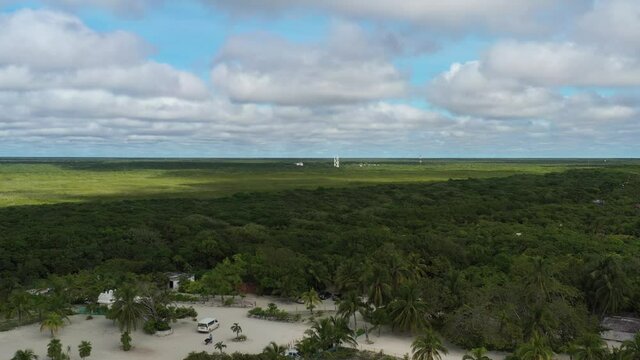 A&eacute;rea descendiendo sobre la densa jungla tropical de Tulum para llegar a Playa Paraiso, el mar caribe y unas pangas en la playa.