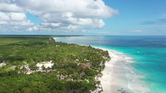 Vista a&eacute;rea panor&aacute;mica de la densa jungla tropical que rodea la playa en Tulum, M&eacute;xico. Un cielo azul nublado y el mar azul turquesa como fondo.