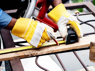 New House Building Project.Foreman engineering construction african Technicians skill carpentry uses tape measure meters wearing blue protective clothing are cutting off wood industrial factory	