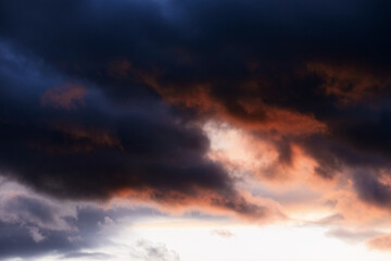 Stormy summer sunset with dark red anb blue clouds. Dramatic weather with atmosphere clouds.