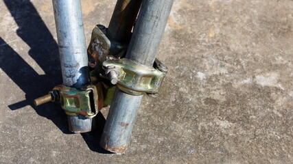 Outdoor scaffold pipe clamp. Scaffolding metal pipe connector and clamp on construction site to strengthen structures on concrete with copy area. Selective focus