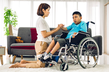 Portrait of asian physiotherapist carer helping and playing with special disabled child health problem by doing exercises sitting in wheelchair in rehabilitation clinic.disability care concept