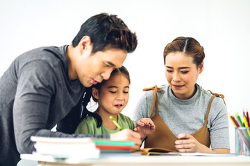 Portrait enjoy happy smiling love asian family father and mother with little asian girl learning and writing in book with pencil making homework at home.Education concept