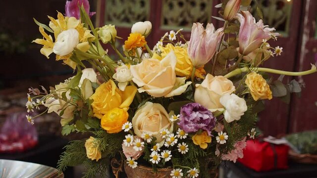 A bucket of colorful flowers standing on outdoor catering table. Table decoration.