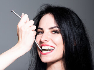 Obraz premium Strong teeth. Closeup of young woman with snow-white smile. Ideal strong white teeth, teethcare. Healthcare, stomatological concept for dentists. Girl biting metallized nail with healthy white teeth.