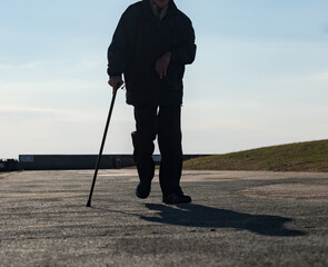 秋の海岸の公園で散歩している障害者の高齢男性の姿