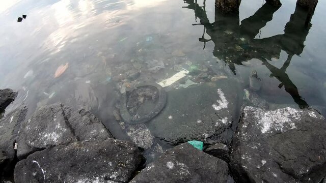 Panning fish eye view of rubbish in the sea water at coastal.