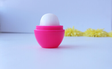 Hygienic lipstick opened in a pink bottle, minimalism. Isolated close-up view of an open white lipstick suitable for branding with corporate logos and advertisements on a white background.
