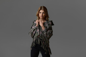 Fototapeta premium portrait of beautiful blonde woman with curly hair in jacket on chair on studio background.