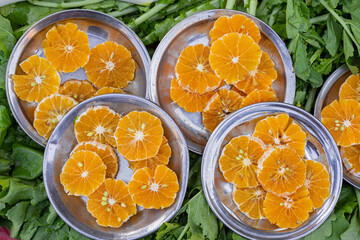 cut oranges in plates on green leaves