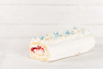 Beautiful white cake roll in front of a white background. The cake has snowflake-shaped confectionery decorations.
