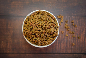 Cat food in a white bowl on a wooden background.