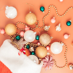 christmas decorations fall out of santa hat on orange background, top view, close up