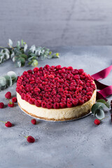 Delicious cheesecake fully covered  with raspberries on light grey background. Beautiful Christmas or Valentine dessert, copy space