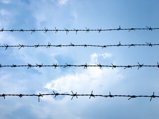 Barbed wire with blue sky background. barbed wire on fence of protected private area.