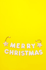 Fototapeta premium Text Merry Chritmas made from wooden letters on yellow background, vertical format