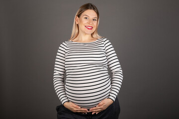 Pregnant woman posing on grey background