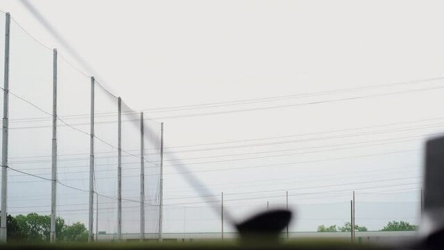 Close-up of golf ball on tee with golf club overlooking driving range at Topgolf