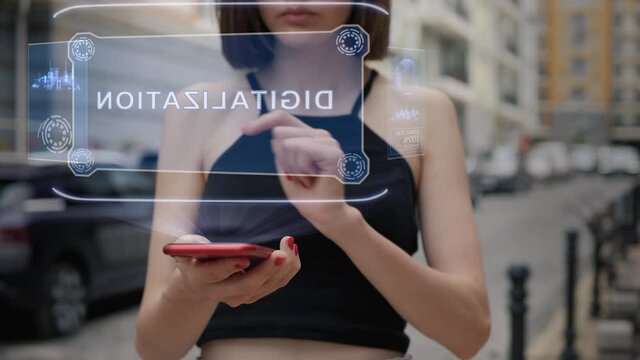 Unrecognizable young adult woman standing on the street interacts HUD hologram with text Digitalization. Girl in black clothes uses technology of the future mobile screen