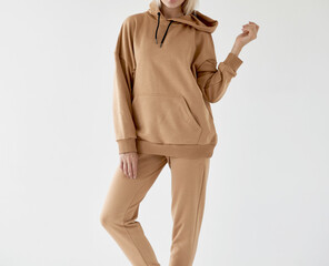 girl wears light brown hoodie and pants. isolated photo of women wearing nude color fleece textile outfit.