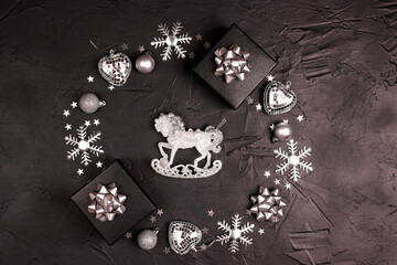 Christmas round frame made of silver decorations with decorative horse on a black background.