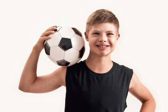 Happy disabled boy with Down syndrome smiling at camera while posing with football isolated over white background