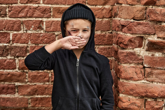portrait of unhappy street boy alone outdoors, caucasian child has dirty face and clothes, dramatic portrait of a little homeless boy, dirty hand, poverty, city, street