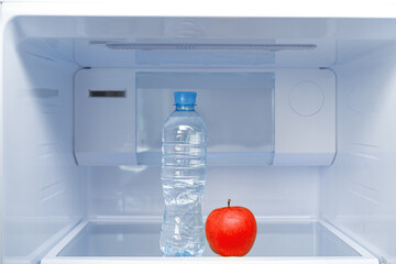 Bottle of water and red apple in fridge