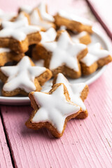 Fototapeta na wymiar Icing gingerbread stars. Traditional Christmas cookies on pink wooden table.