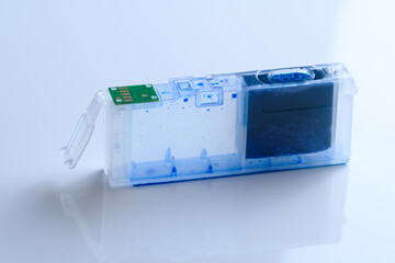 Eine einzelne leere blaue Tintenpatrone / Cartridge steht seitlich auf einem neutralen weißen...
