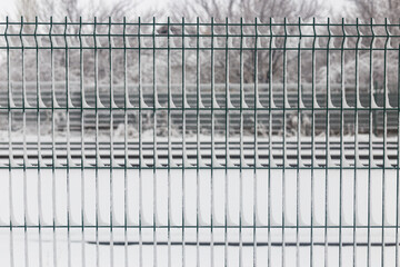 Fototapeta na wymiar Snow-covered mesh. The lattice fence is covered with fresh snow. Winter background texture. White background texture