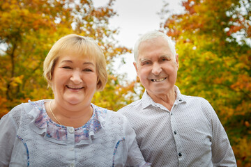 Elderly couple walking in the park on an autumn day.