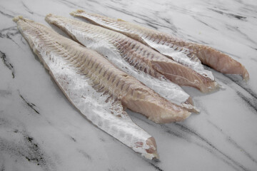 Gastronomy. Fresh seafood ingredients for cooking. Closeup view of raw hake filets on the white...