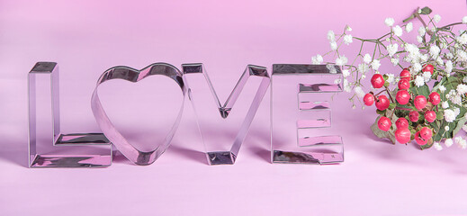 Decorative metal letters, love text, red flowers, greeting card on pink background. Declaration of love and term of affection concept.