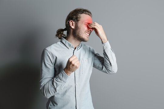 Young man suffering from headache on grey background