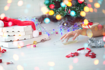 Man  hand of a drunken reaches out to the bottle with alcohol. A drunk man lies on the floor against the background of Christmas lights. Consequences of the Christmas Eve.