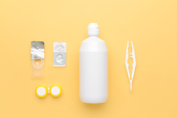 Container with contact lenses, solution and tweezers on color background