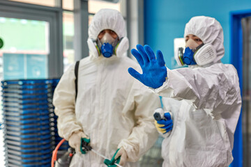 man in protective hazmat suit stops, does not let to enter building, don't allow. during coronavirus epidemic. focus on hand