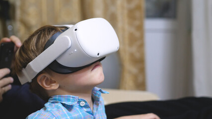 Child wearing virtual reality glasses and watching vr 360 video at home